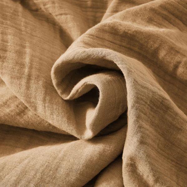 Tissu beige en gaze de coton doux et léger avec texture froissée visible de près