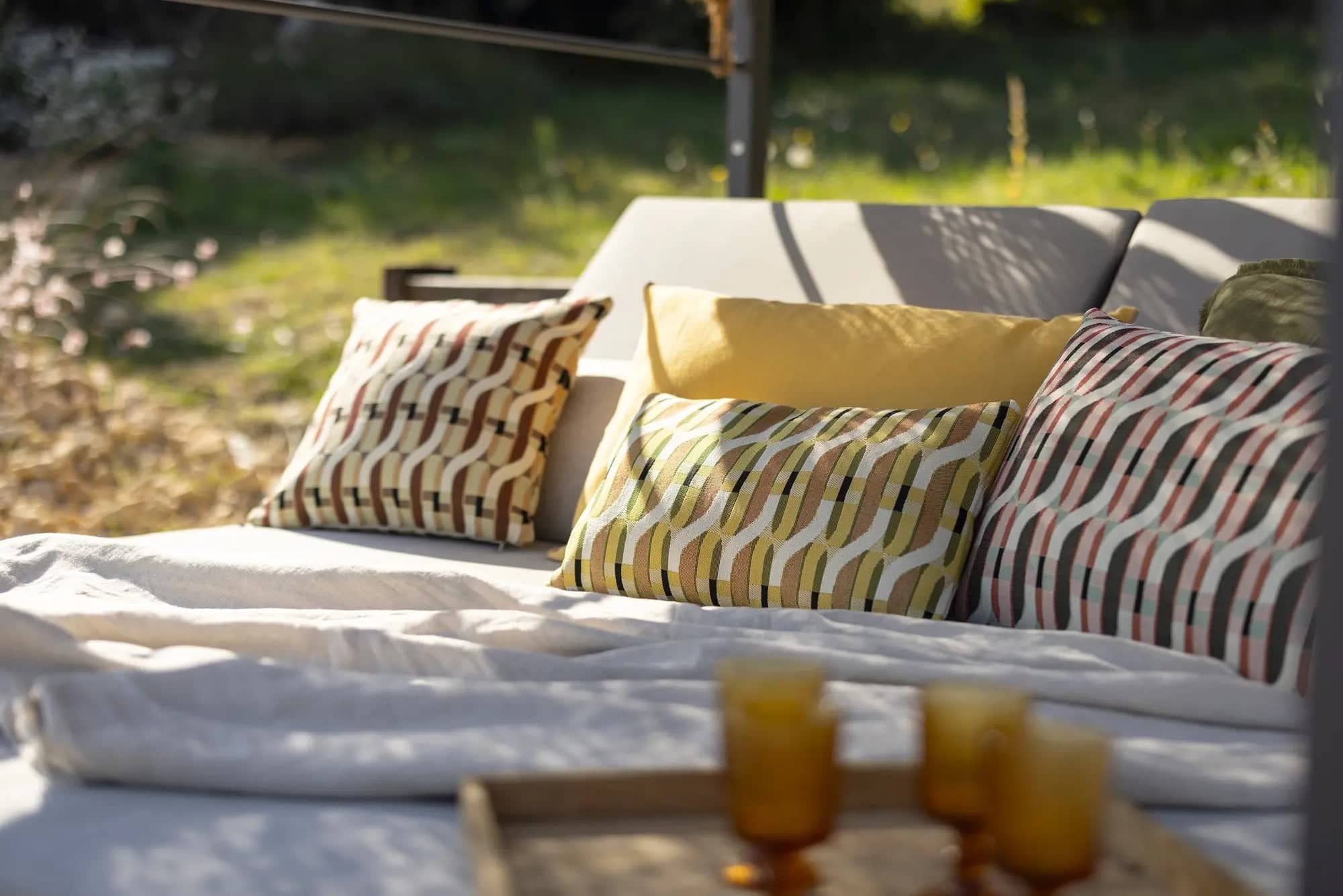 Collection de coussin outdoor design avec motifs modernes sur canapé extérieur ensoleillé