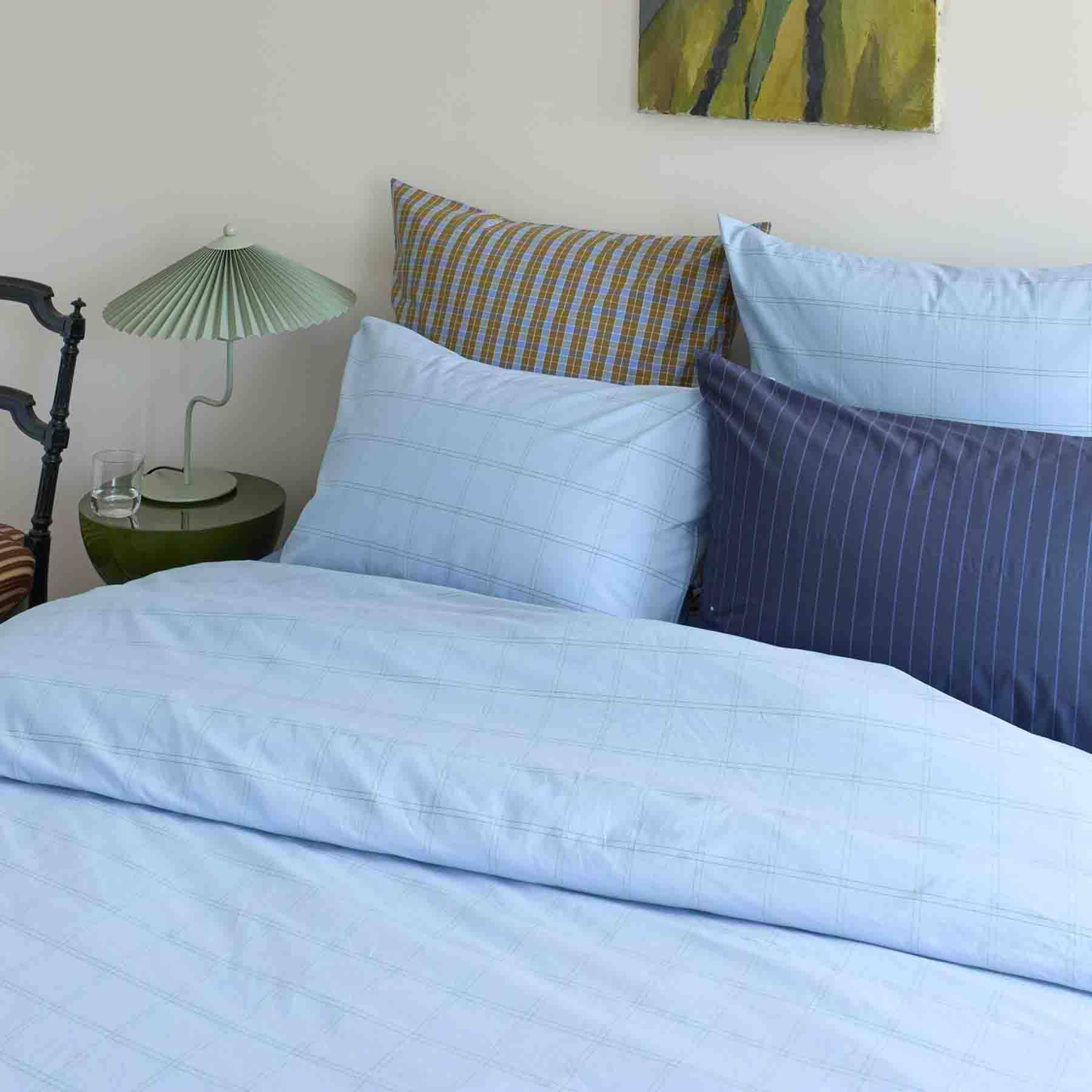 Ensemble de taie d'oreiller coton haut de gamme et housse de couette bleu clair sur lit moderne
