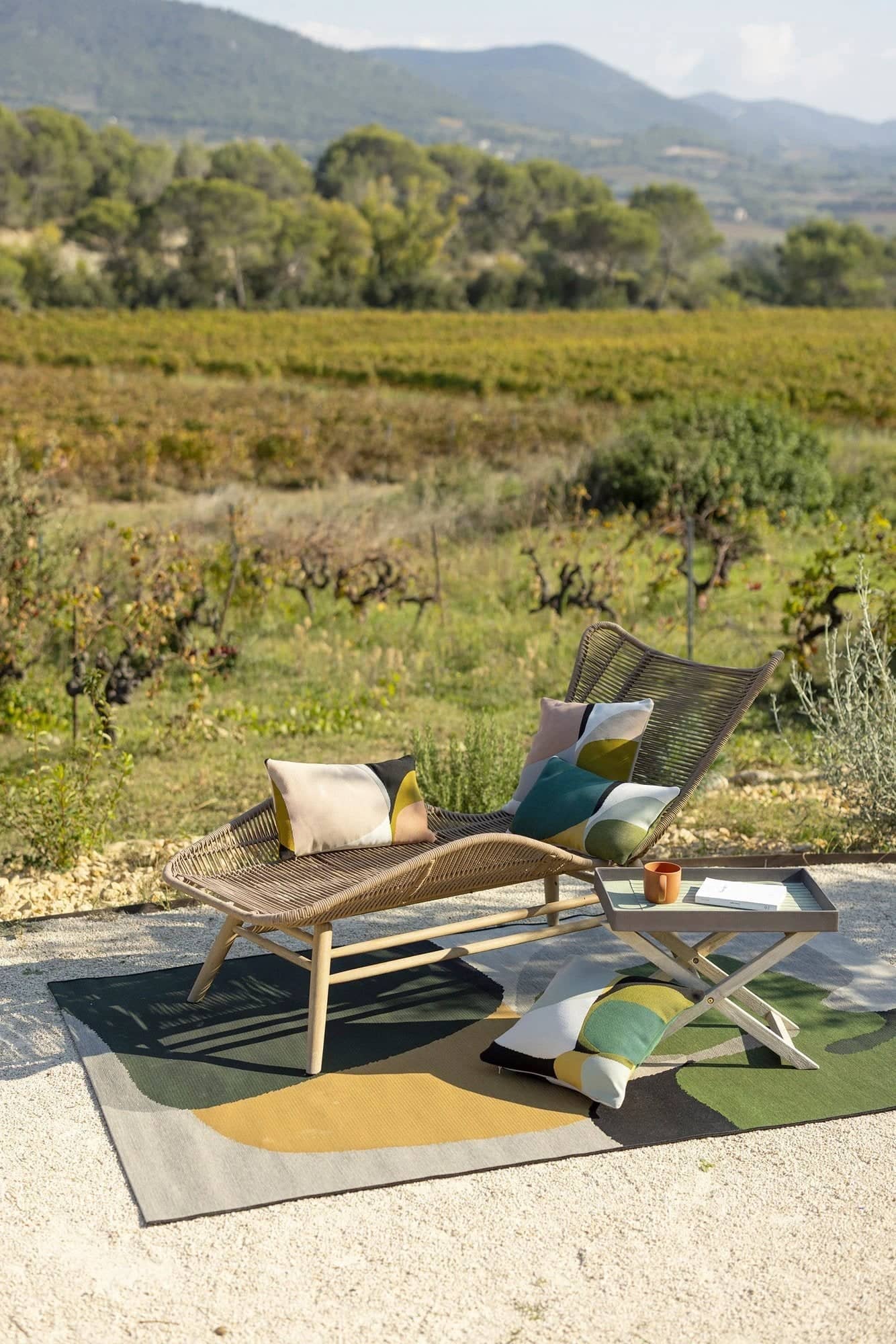 Espace extérieur avec chaise longue et coussins Leana Linge de Maison dans un cadre naturel avec vue sur les collines