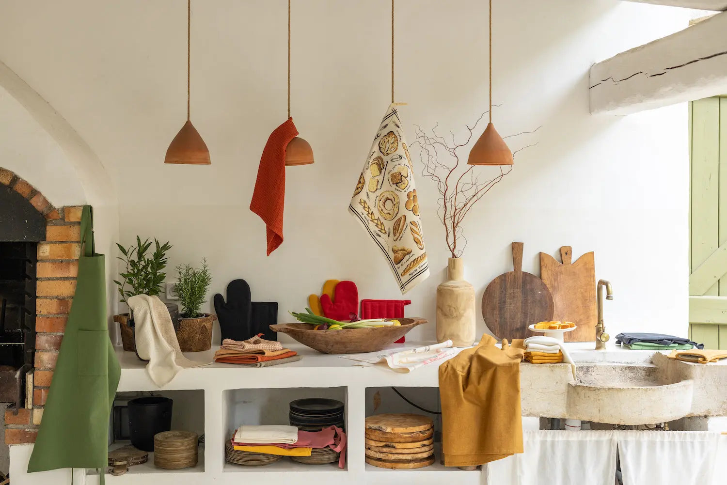 Collection de linge de cuisine fabriqué en France avec torchons et gants dans une cuisine rustique