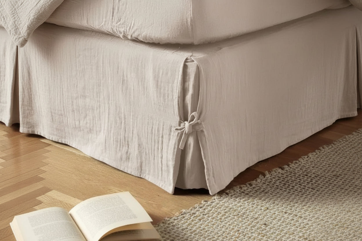 Cache sommier coton beige avec nœud décoratif habillant le bas du lit dans une chambre chaleureuse