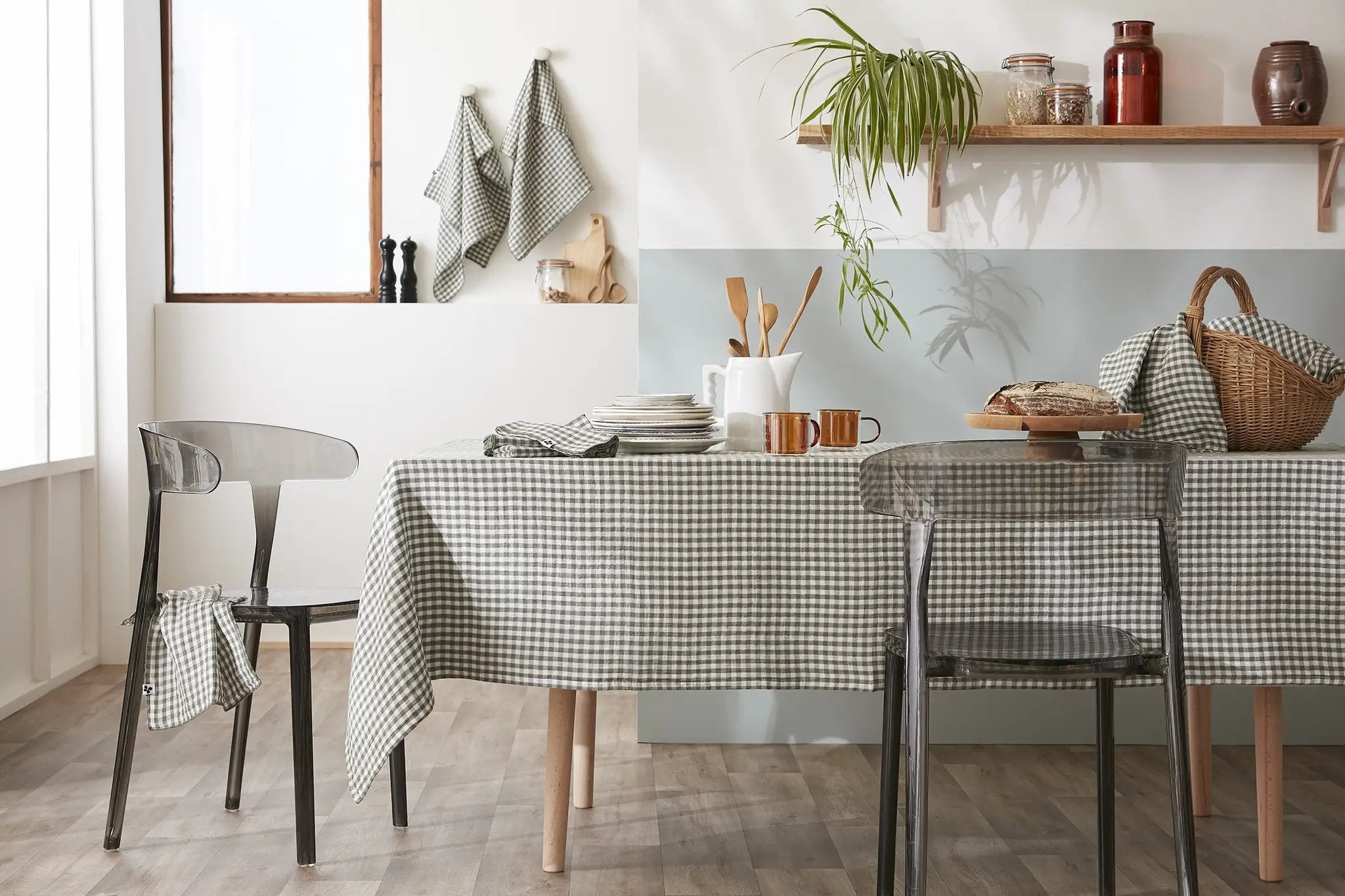 Table extérieure ronde avec nappe gaze de coton verte entourée de chaises en osier dans un champ fleuri