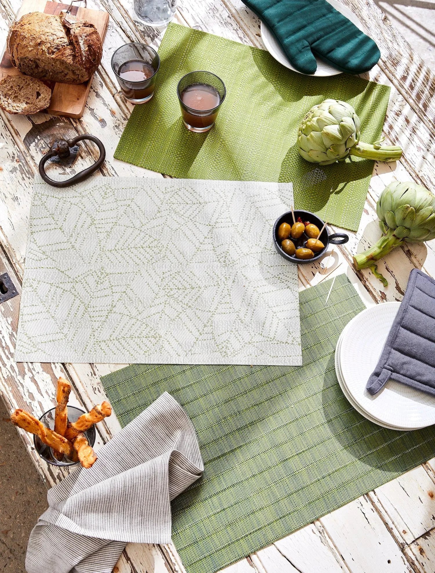 Set de table PVC tissé Winkler en vert et blanc sur table rustique avec pain, olives et légumes