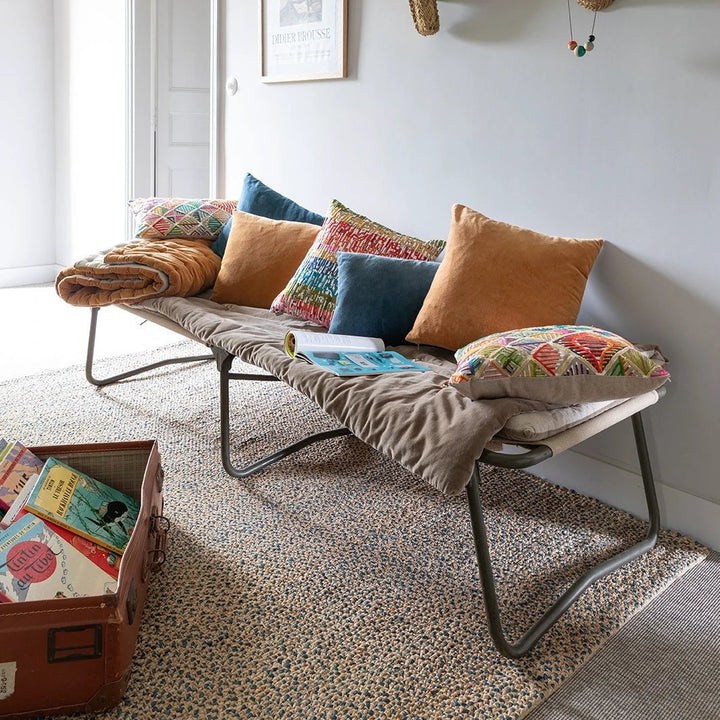 Coussins décoratifs en velours colorés installés sur un banc moderne avec couverture beige
