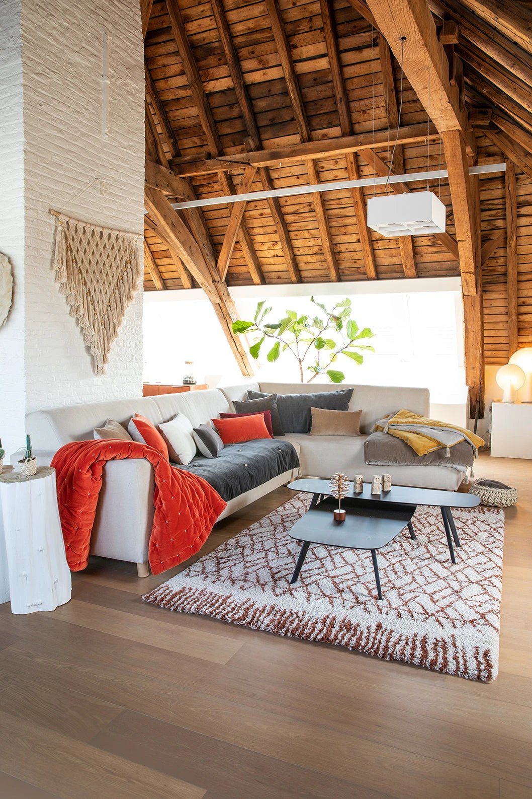 Salon avec canapé blanc et coussins décoratif en velours sous plafond en bois