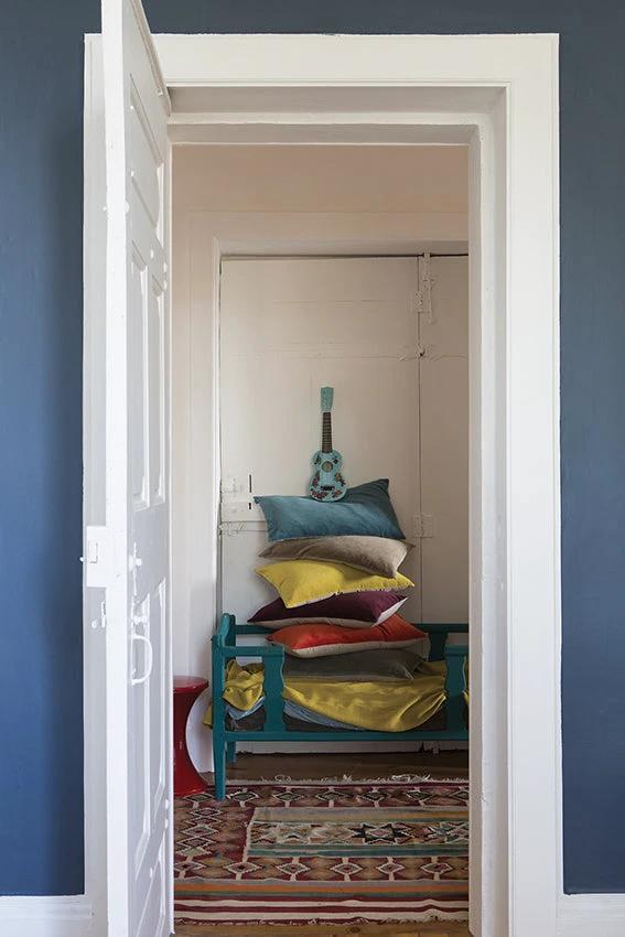 Pile de coussins décoratif en velours de différentes couleurs sur un banc bleu
