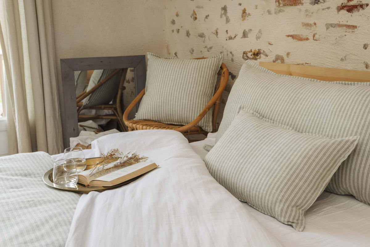Coussin déhoussable à rayures beiges sur lit avec déco naturelle par L'effet papillon