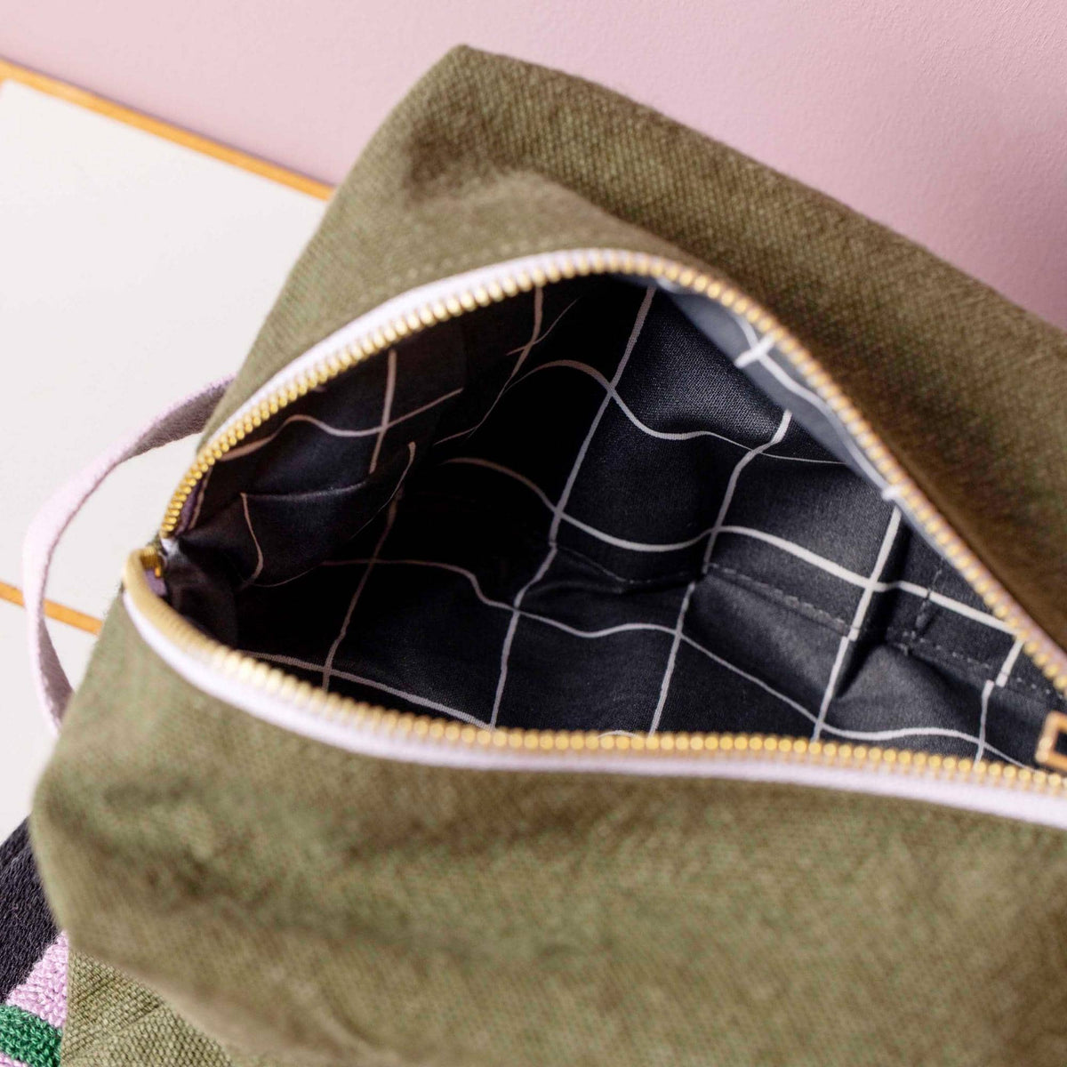 Trousse cube Daddy Cool Kale : vue ouverte montrant l’intérieur noir à quadrillage blanc et la fermeture dorée sur fond kaki.