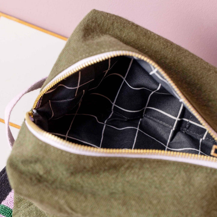 Trousse cube Daddy Cool Kale : vue ouverte montrant l’intérieur noir à quadrillage blanc et la fermeture dorée sur fond kaki.