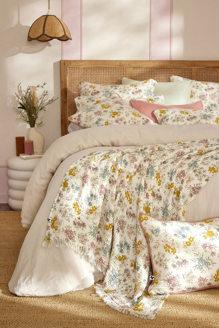 Plaid à franges floral délicat sur lit avec tête de lit en osier pour décoration chaleureuse